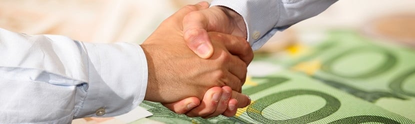 Poignée de mains au dessus de billets euros