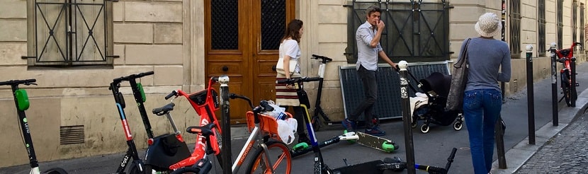 Des vélos et scooters électriques garés sur un trottoir 