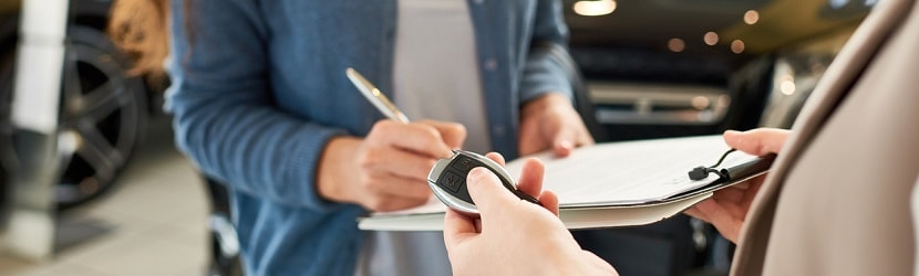 une femme en train de signer contrat d'achat de vehicule