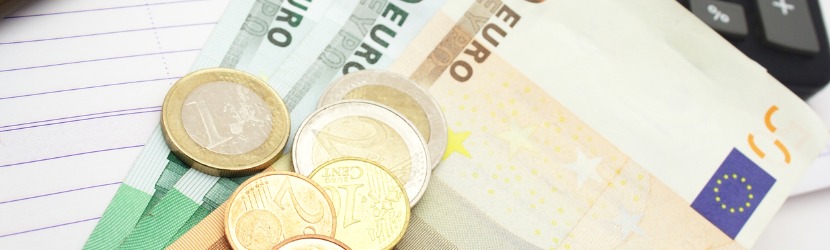 Tas de pièces de monnaie sur des billets de 50 et 100 euros