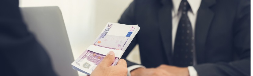 Homme d'affaites tendant une liasse de billets de 500 euros a un autre homme.